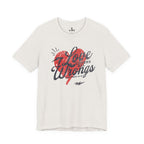 Cream Love Covers All Wrongs tee with a red heart and dark script lettering across the front.
